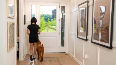 woman-walking-dog-in-house woman in sports wear with dog walking down well lit hallway, about to go outside